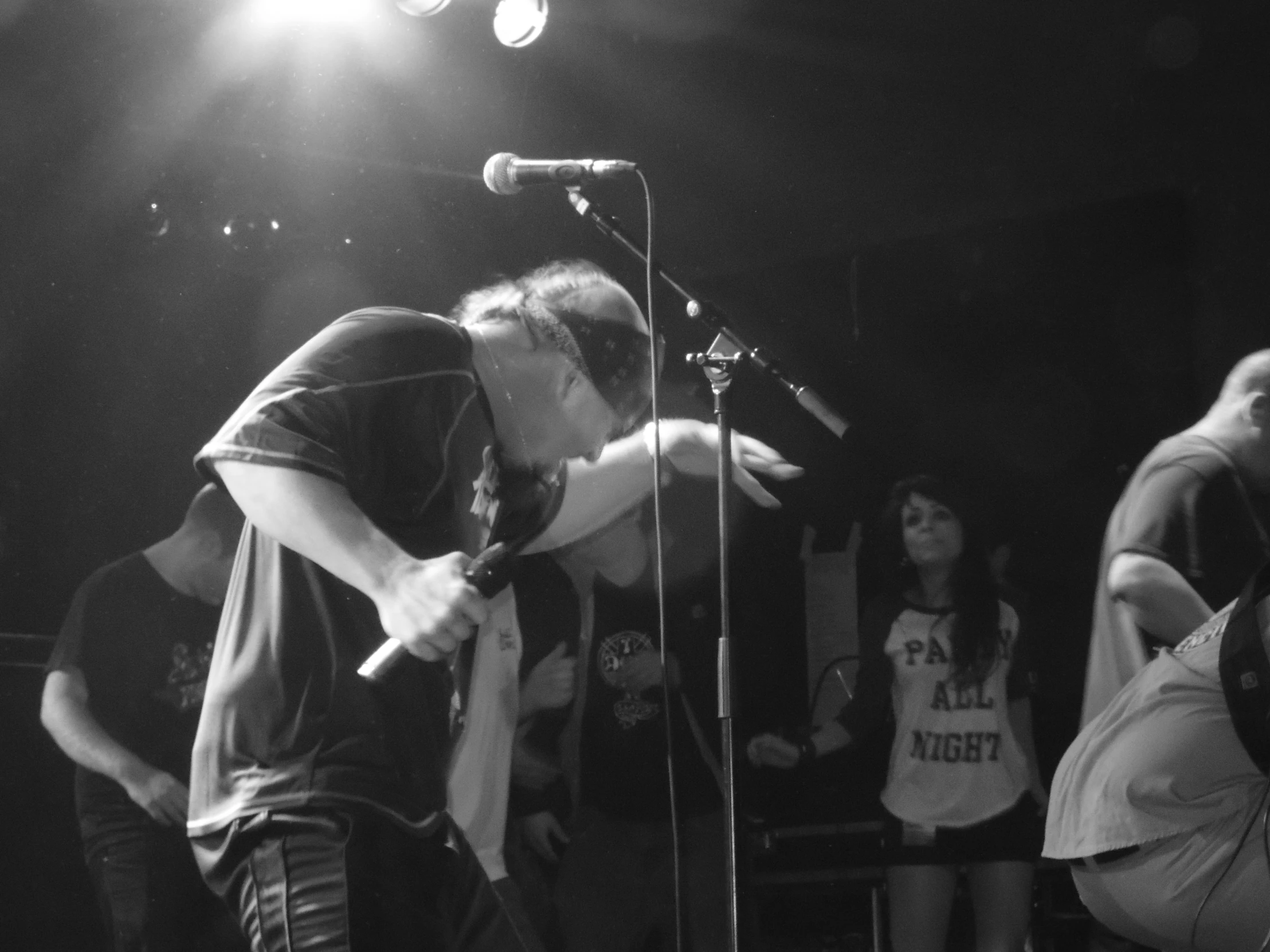 people are singing into a microphone and a man is holding a guitar