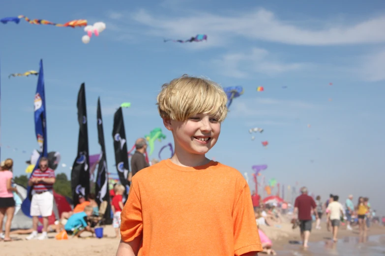 a boy is on the beach and there are many kites flying in the air