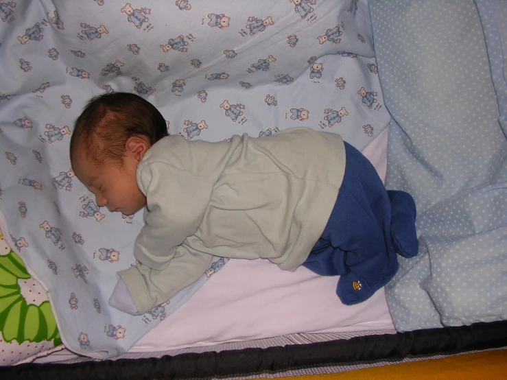 a baby sleeps peacefully on a blanket in a bed