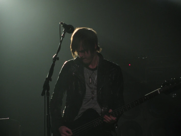 a young male playing the bass while standing on stage