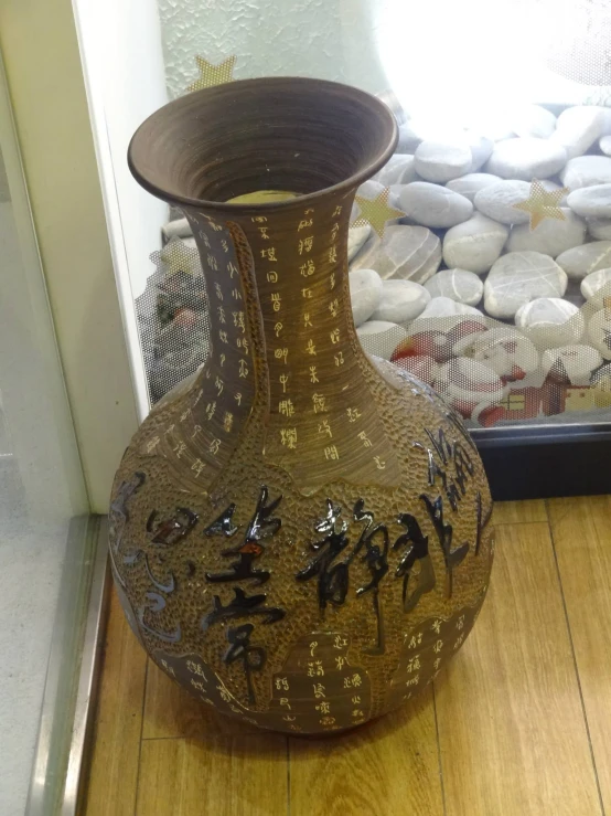 oriental vase displayed in front of wall with rocks in background
