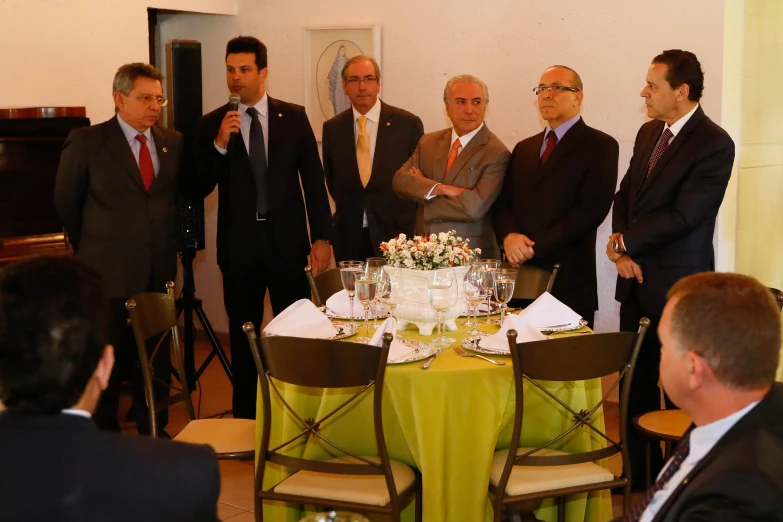 several men in suits gather around a table