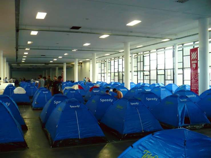 a lot of blue tents sit in a large building