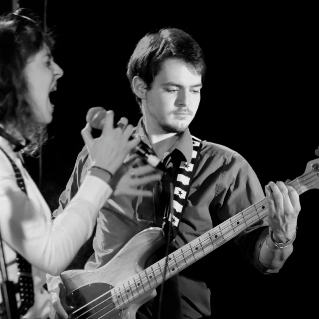 two men standing next to each other and playing guitar