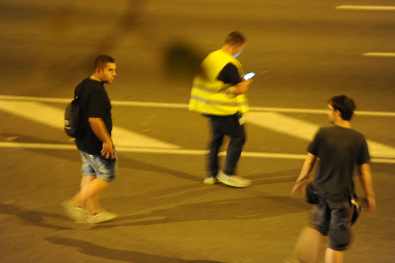 two men walk down a street at night