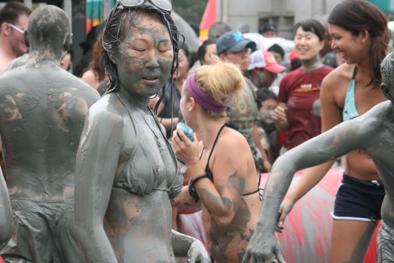 women covered in mud are walking along a crowded street