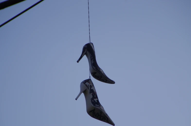 a pair of shoes hanging from a wire against a blue sky