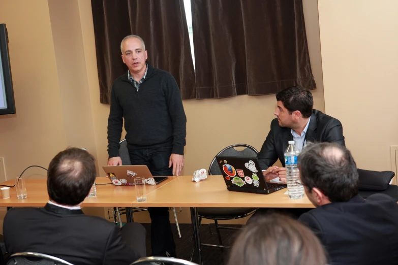 people are sitting at a table with three other men