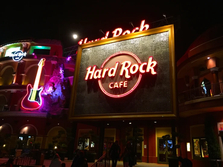 a neon sign advertising hard rock cafe with neon light on the side of the building