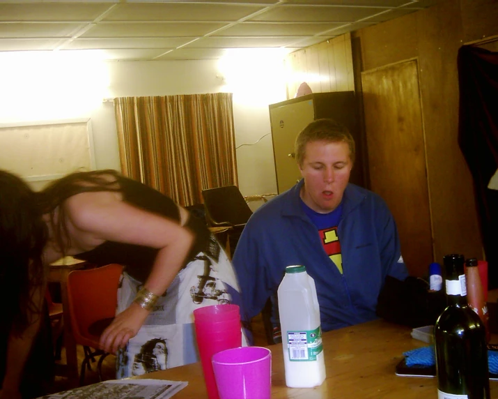 three people at a table with bottles of wine and cups