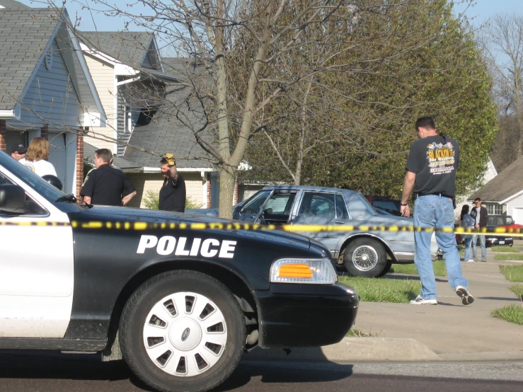 police cars parked in front of people outside the house