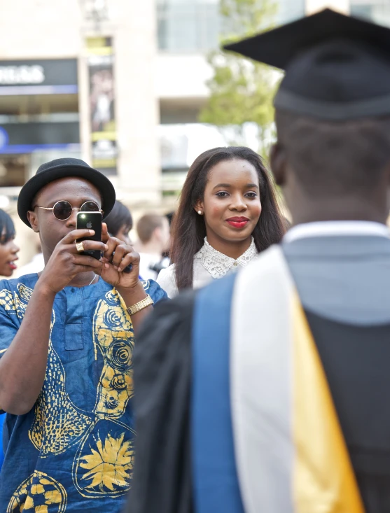 a person dressed in a graduation outfit looks at his cell phone