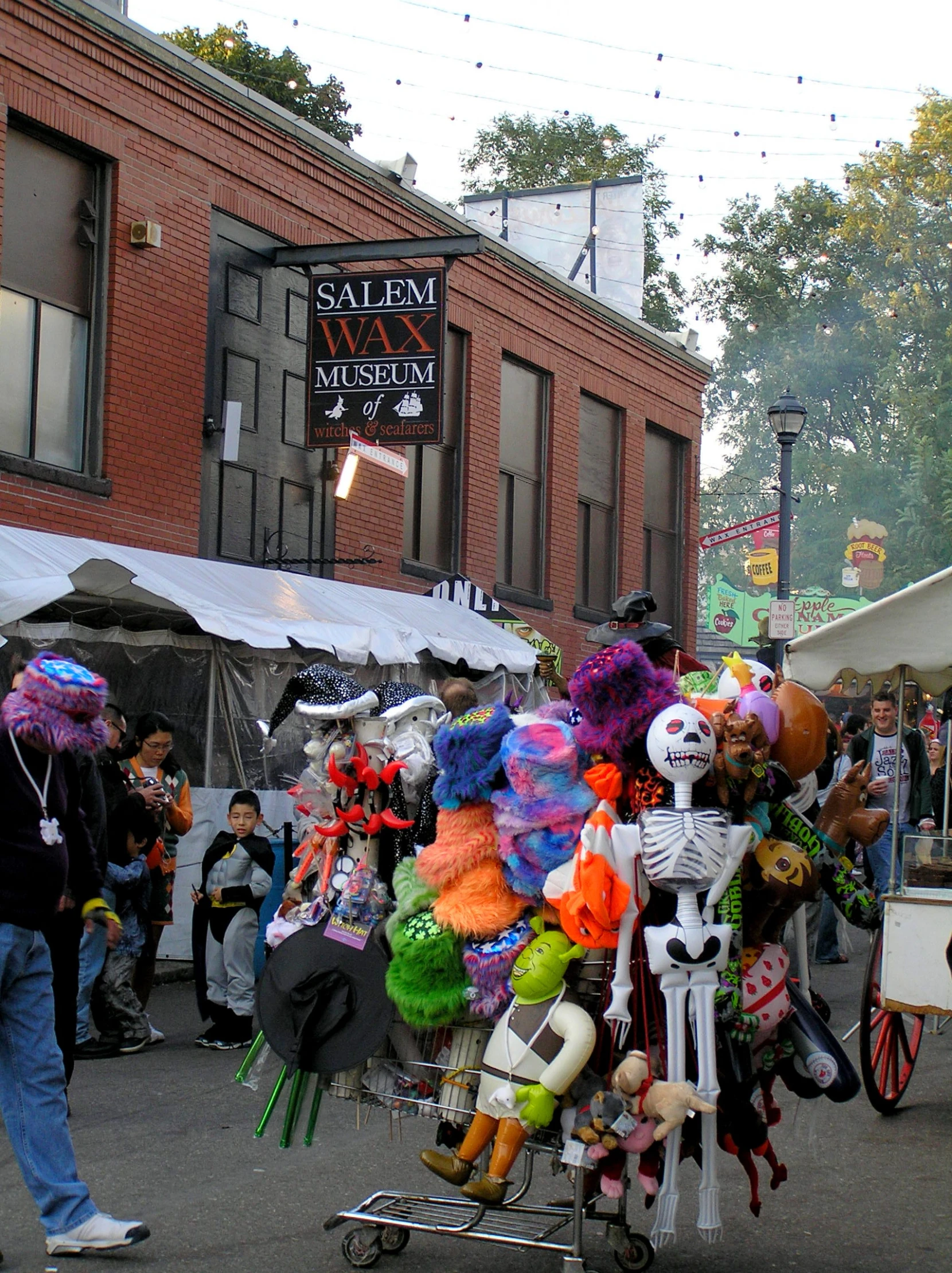 people walking down the street past an outdoor flea market