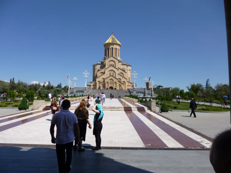 people walking around outside a building, as well as steps leading up to it