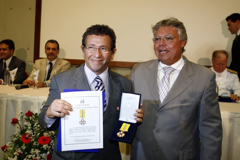 two men posing for the camera and holding awards