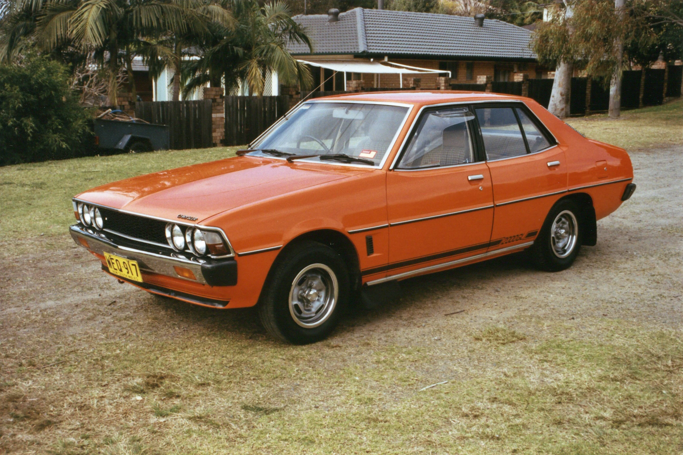 a bright orange car parked in front of a house