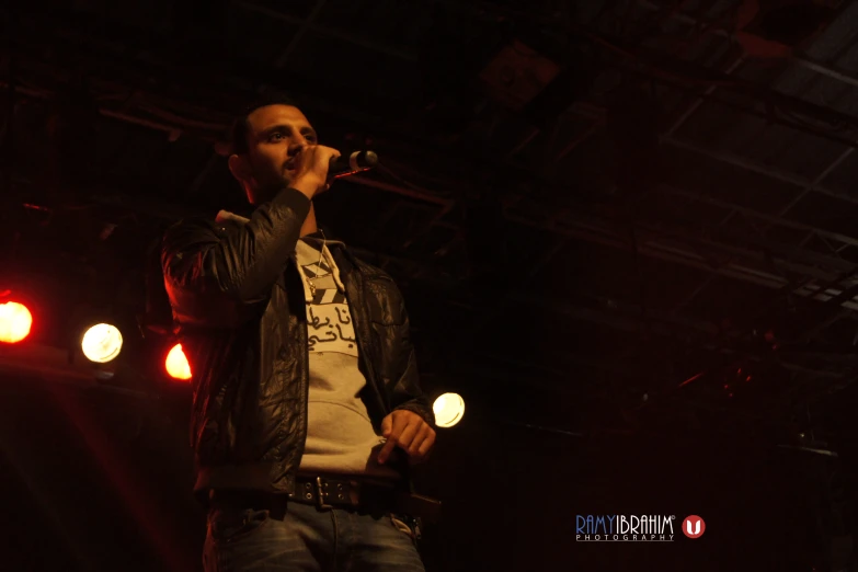 a man on stage singing and lights streaming through the background