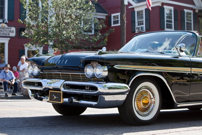 a classic car parked on the street in front of a red building