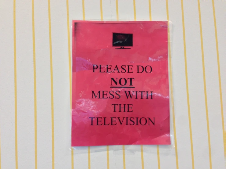 a sign posted on the wall saying please do not mess with the television