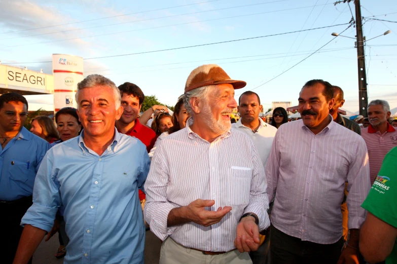 an older man wearing a hat and some other people