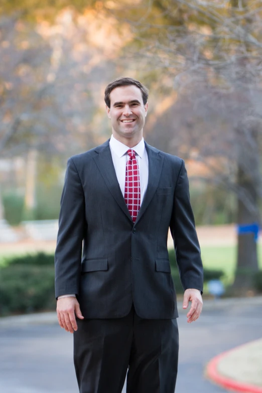 a man wearing a suit stands and smiles