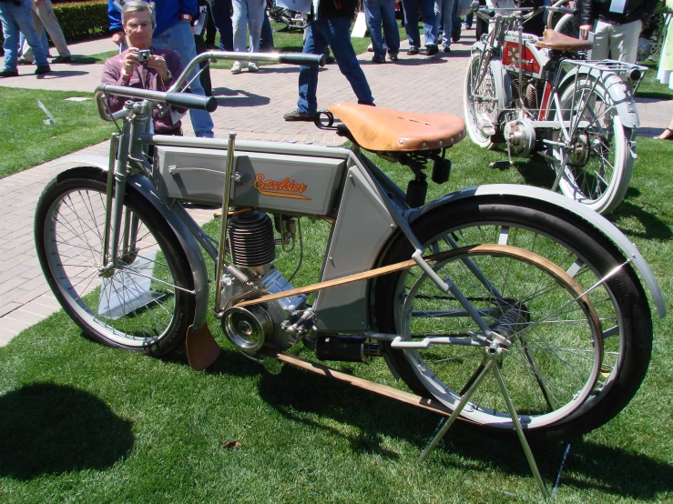 an old motorcycle sits on the grass in front of people