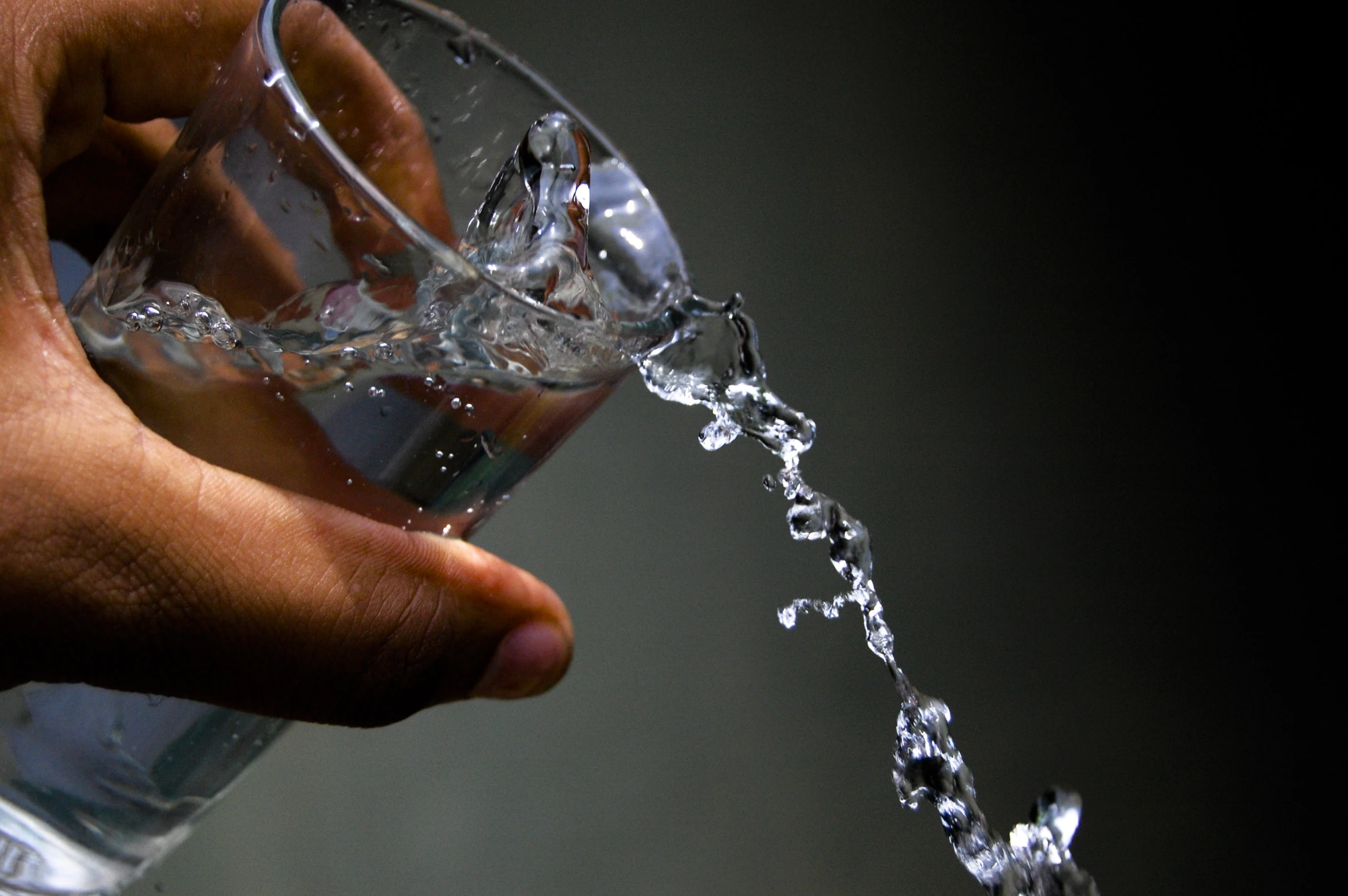 someone holding a glass of water that is pouring from it