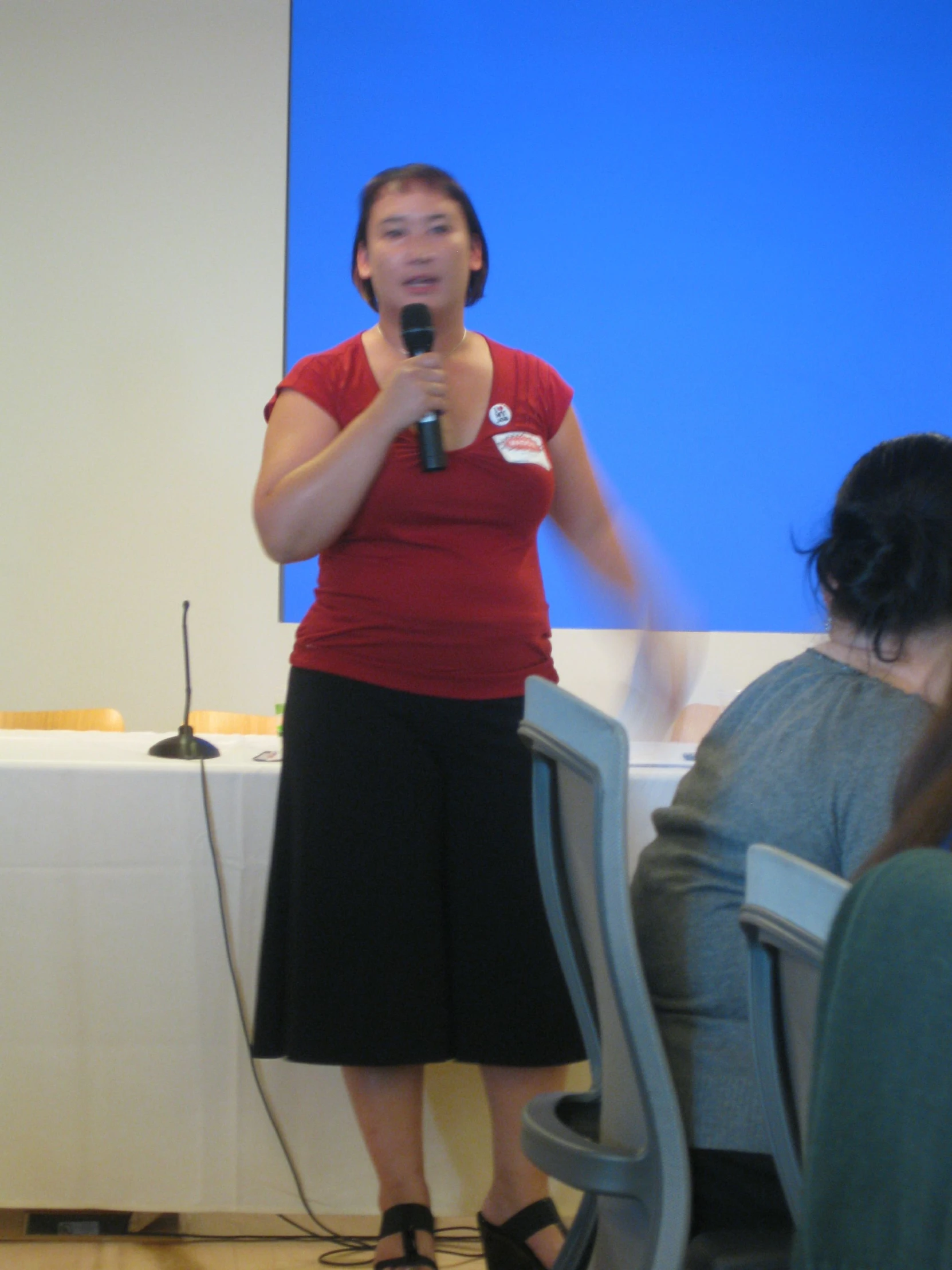 a woman standing in front of a microphone while holding a phone