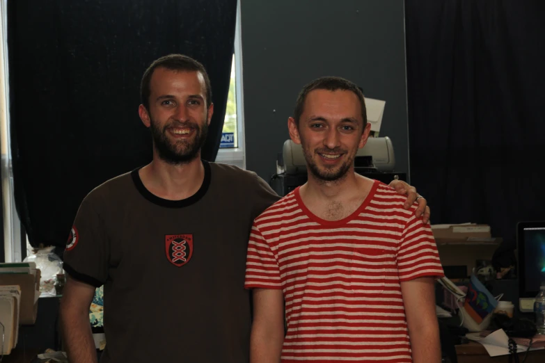 two men standing next to each other in an office