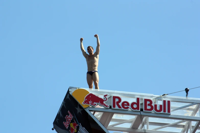 a man on the roof of a building with his arms in the air