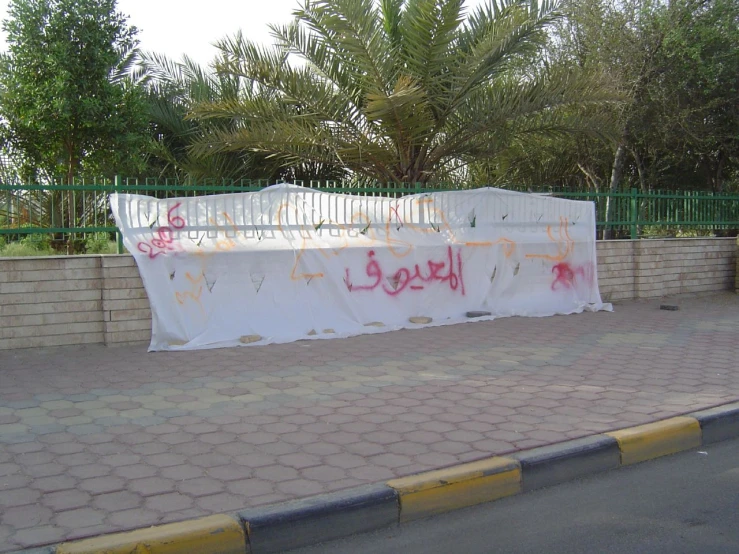 a street view of the side walk and a wall with writing on it