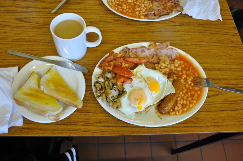 a table topped with plates of food next to cups and coffee