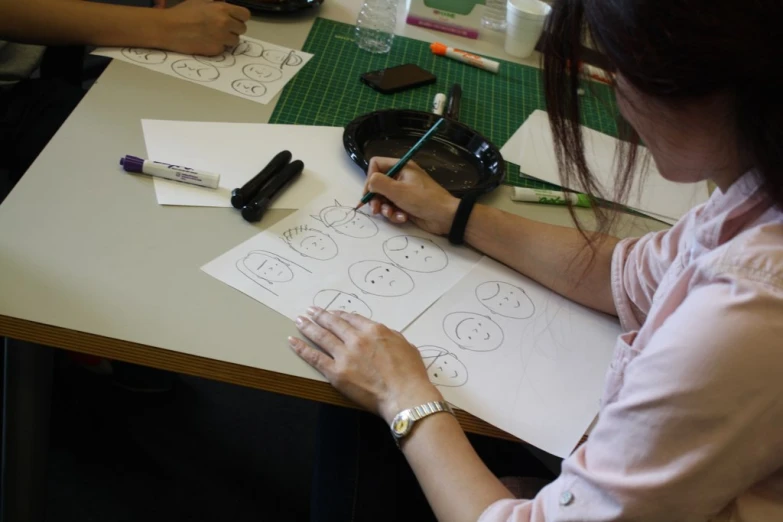 woman creating a face on white paper with pencils