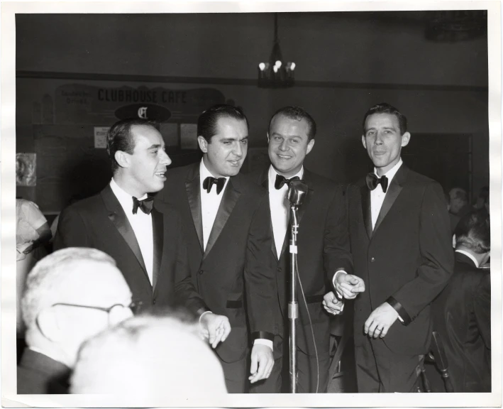 a black and white po of three men standing in front of microphones