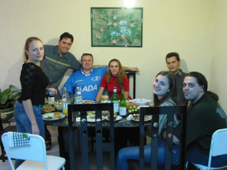 several friends posing for the camera at a dining table