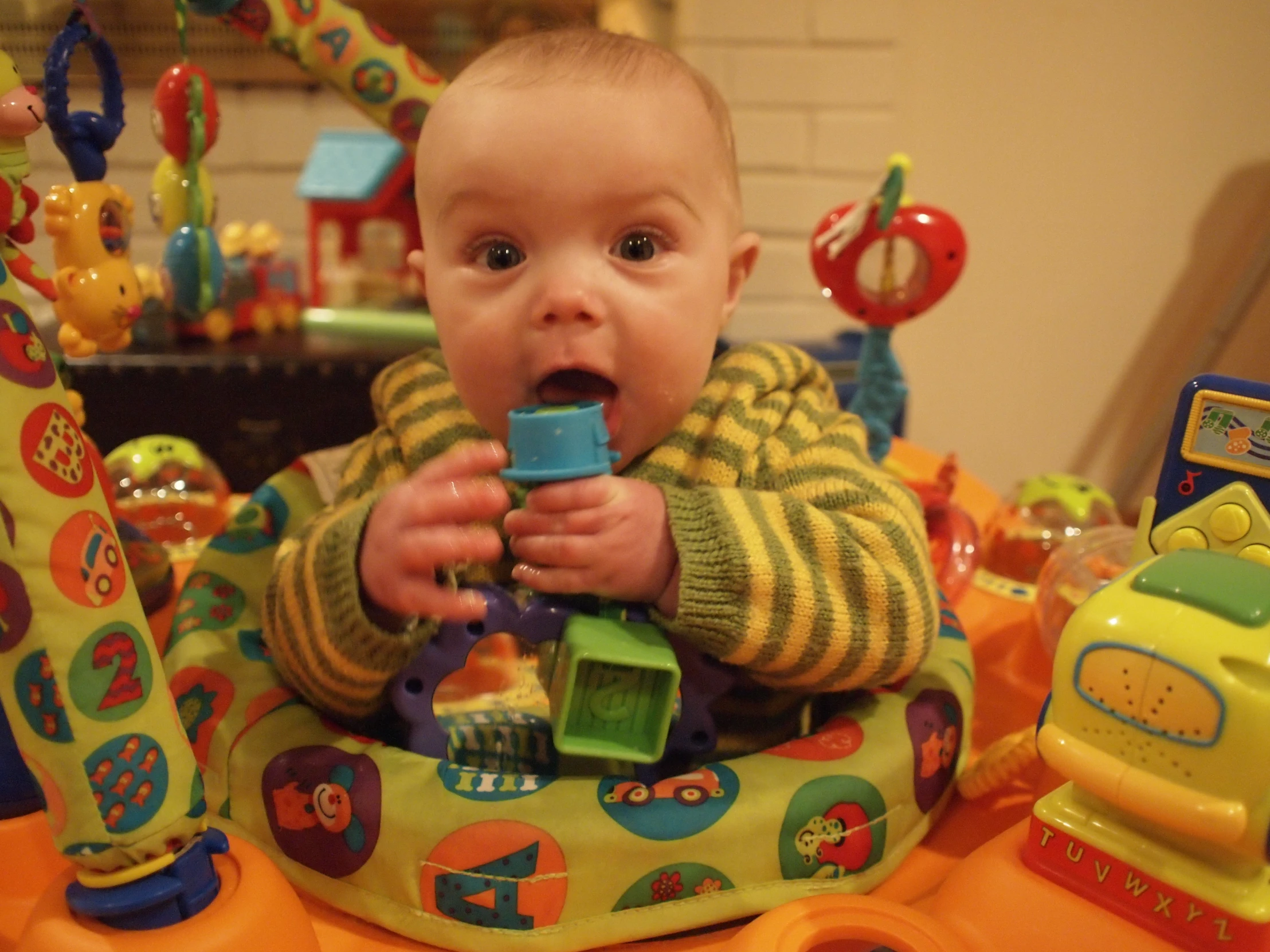 a baby in an inflatable ball seat chewing on toy