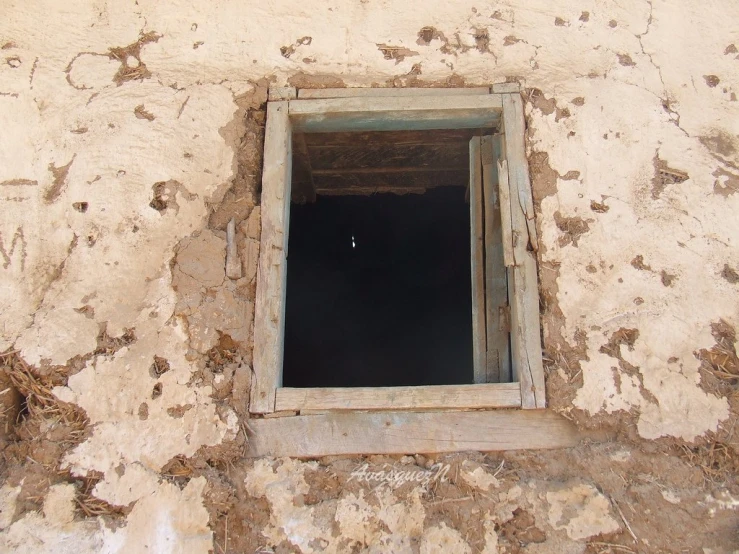 a window on a white building with chipped paint