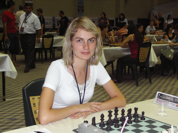 a woman sitting at a table with a large chess board