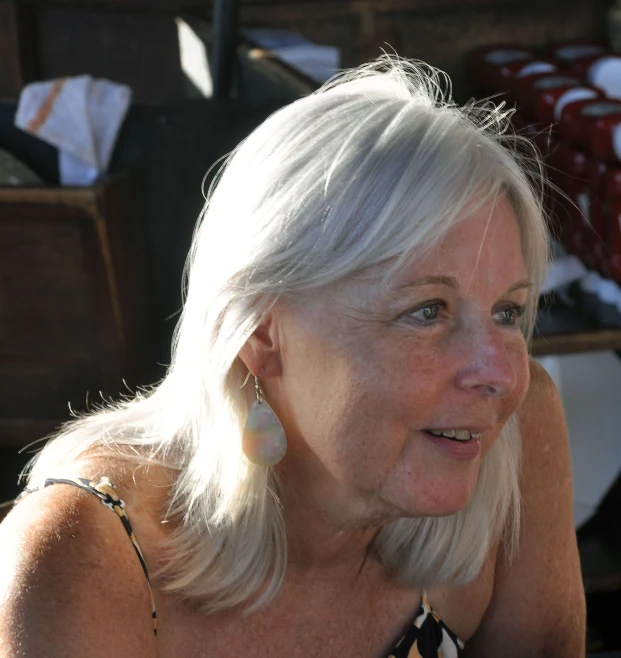 a woman with white hair and earrings looking away from the camera