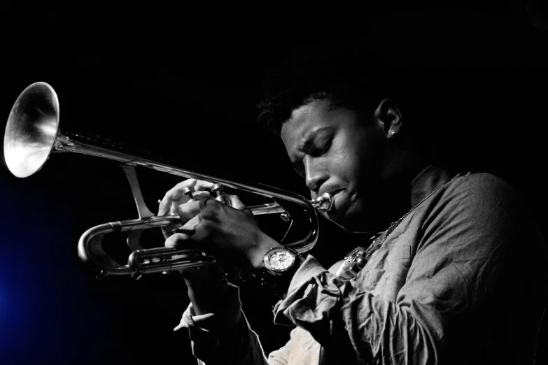 a man plays his trumpet as he stands in the dark