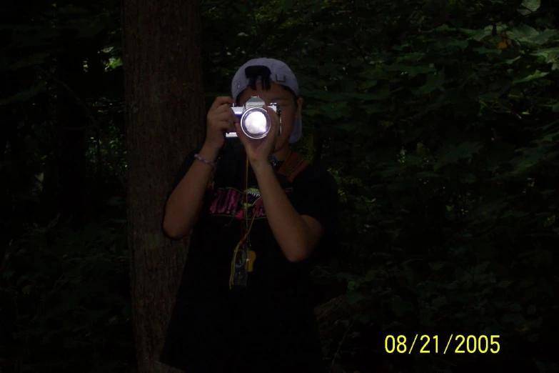 a woman taking a po with her camera in the woods