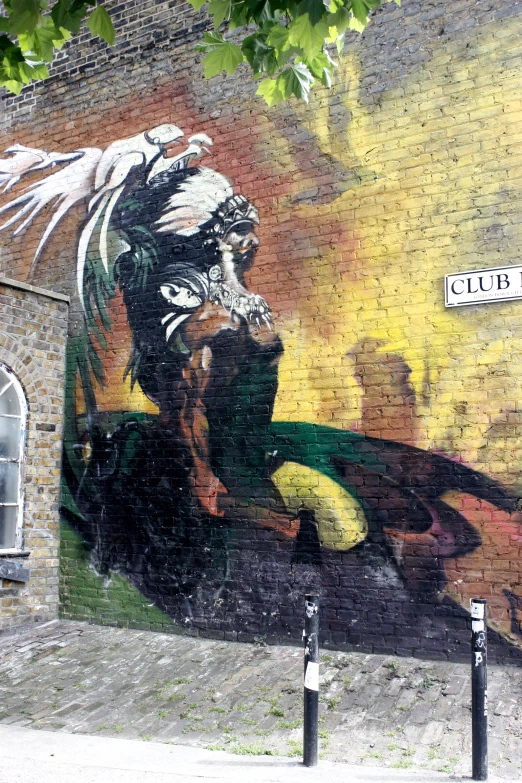 a mural in front of a brick building shows a  with an eagle, a sword and some other figures