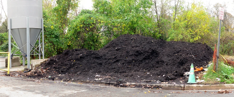 an overflowing pile of compost at a road side corner