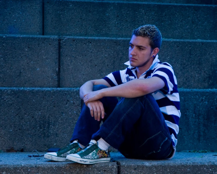 a man sitting on steps looking bored with his sneakers