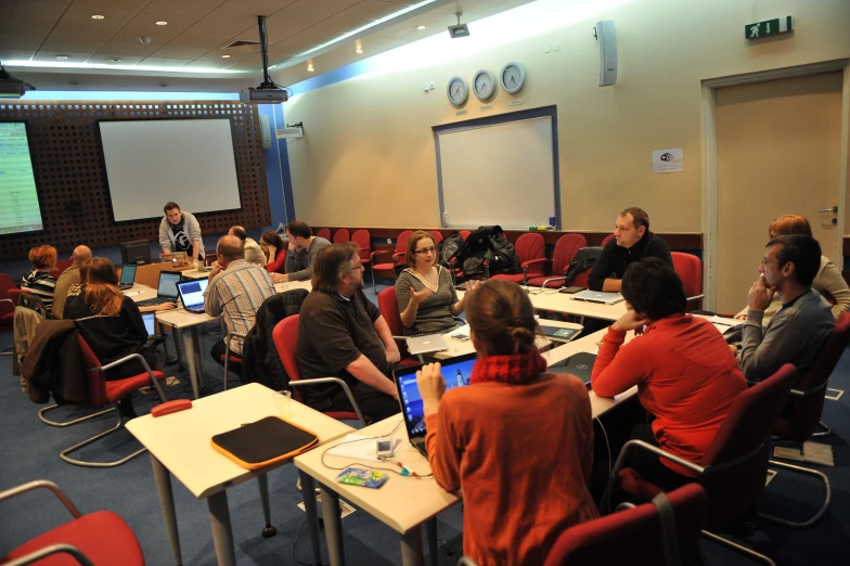 a group of people sitting at desks with laptop computers