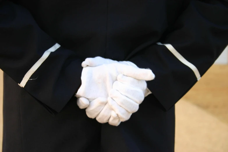 a man with a jacket and white gloves holding the hand of another person