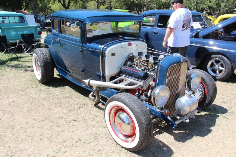 an antique  rod car parked on a lot next to other vehicles