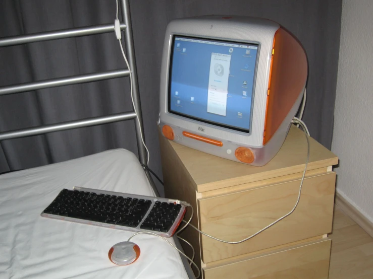 a computer monitor and keyboard on a small nightstand