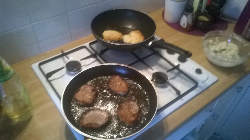 four hamburger patties frying in a pan on the stove
