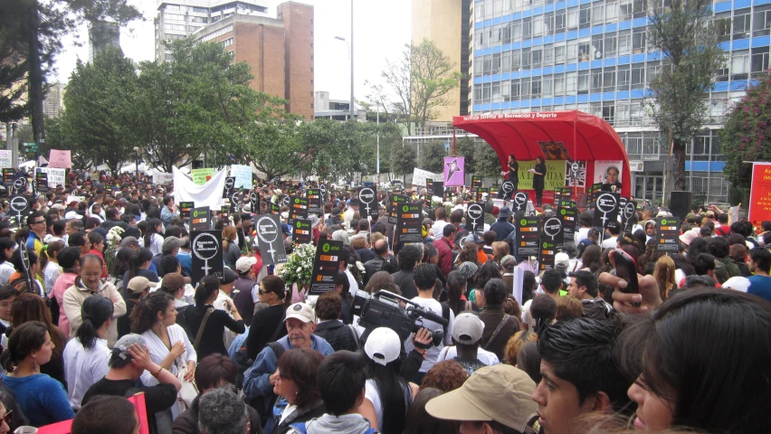 a large crowd of people walk down a crowded sidewalk